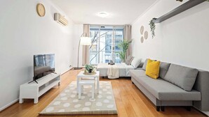 Un salon moderne avec un canapé, un téléviseur et une petite table sur laquelle est posée une plante.