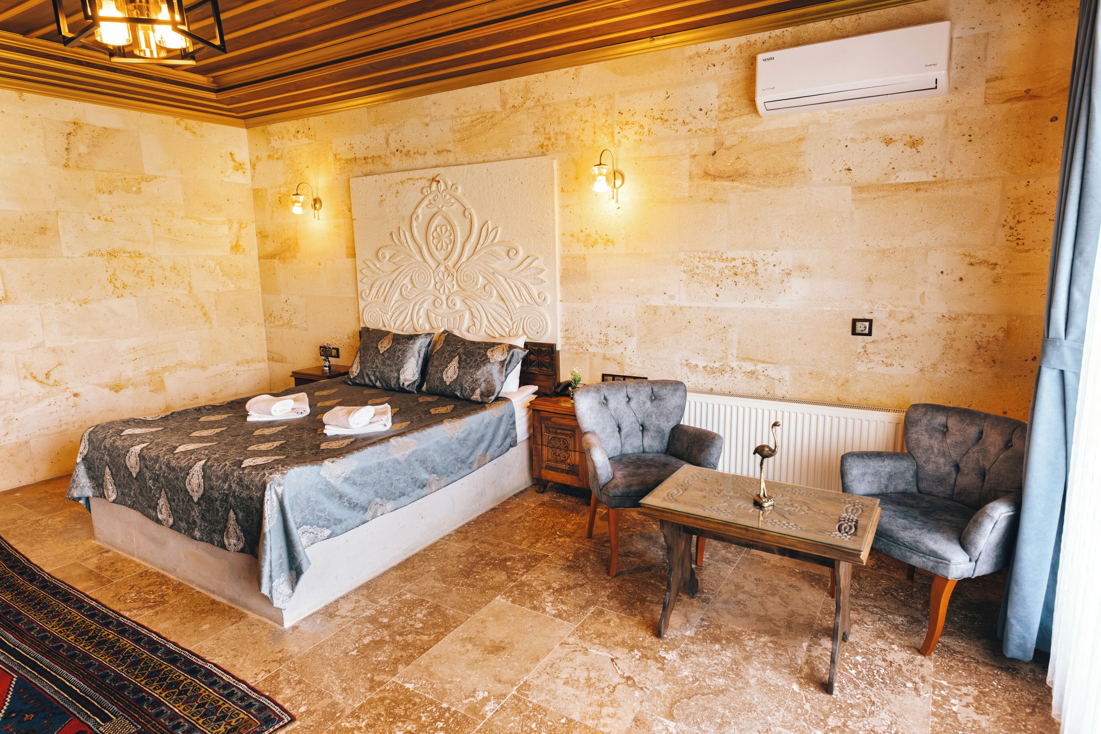 A bedroom with a bed, a chair, a table, and a wall-mounted air conditioner.
