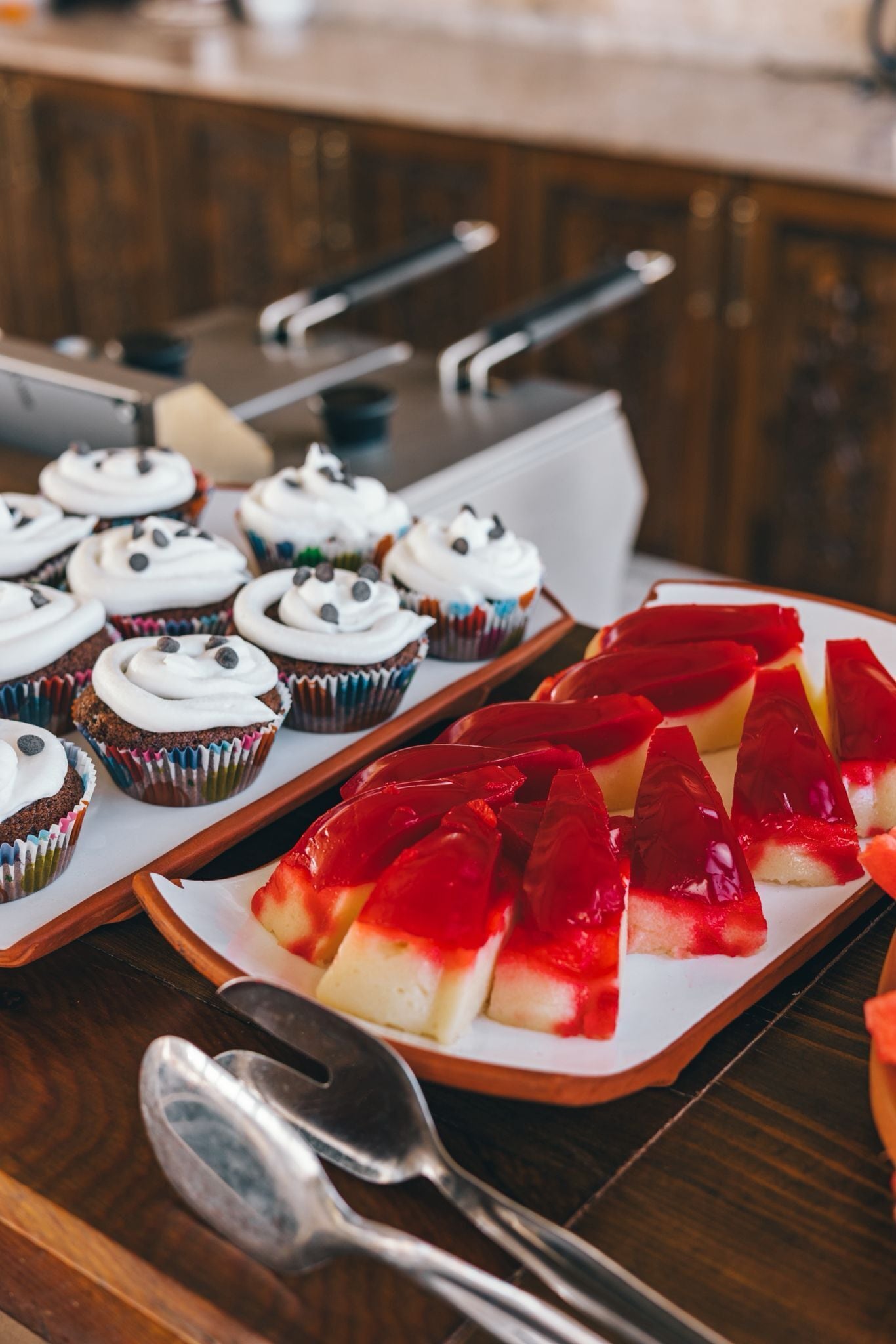 Eine Tablett mit Cupcakes und ein Stück roter Marmorkuchen auf einem Holztisch.