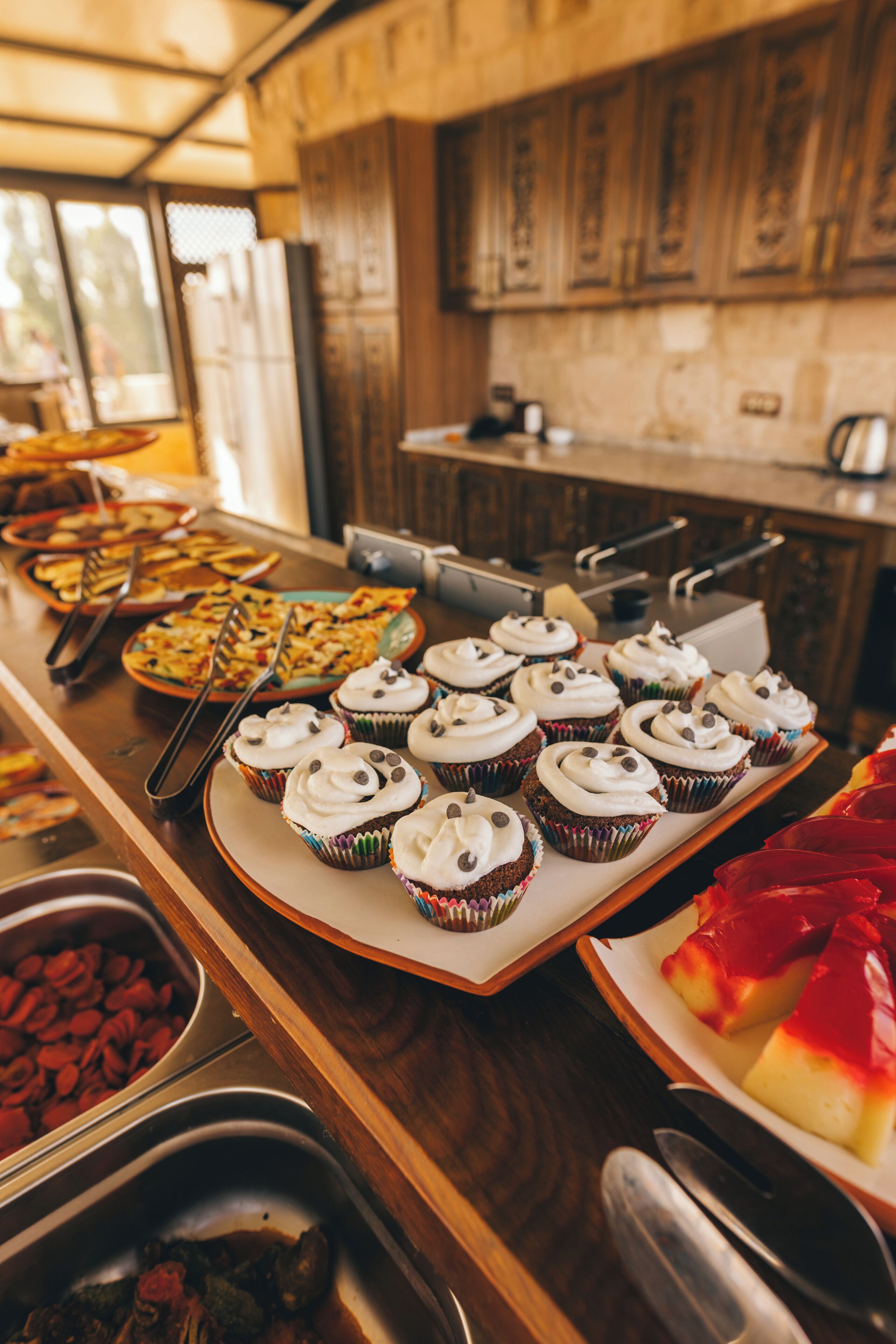 A buffet with various food items including cupcakes and a red dessert.
