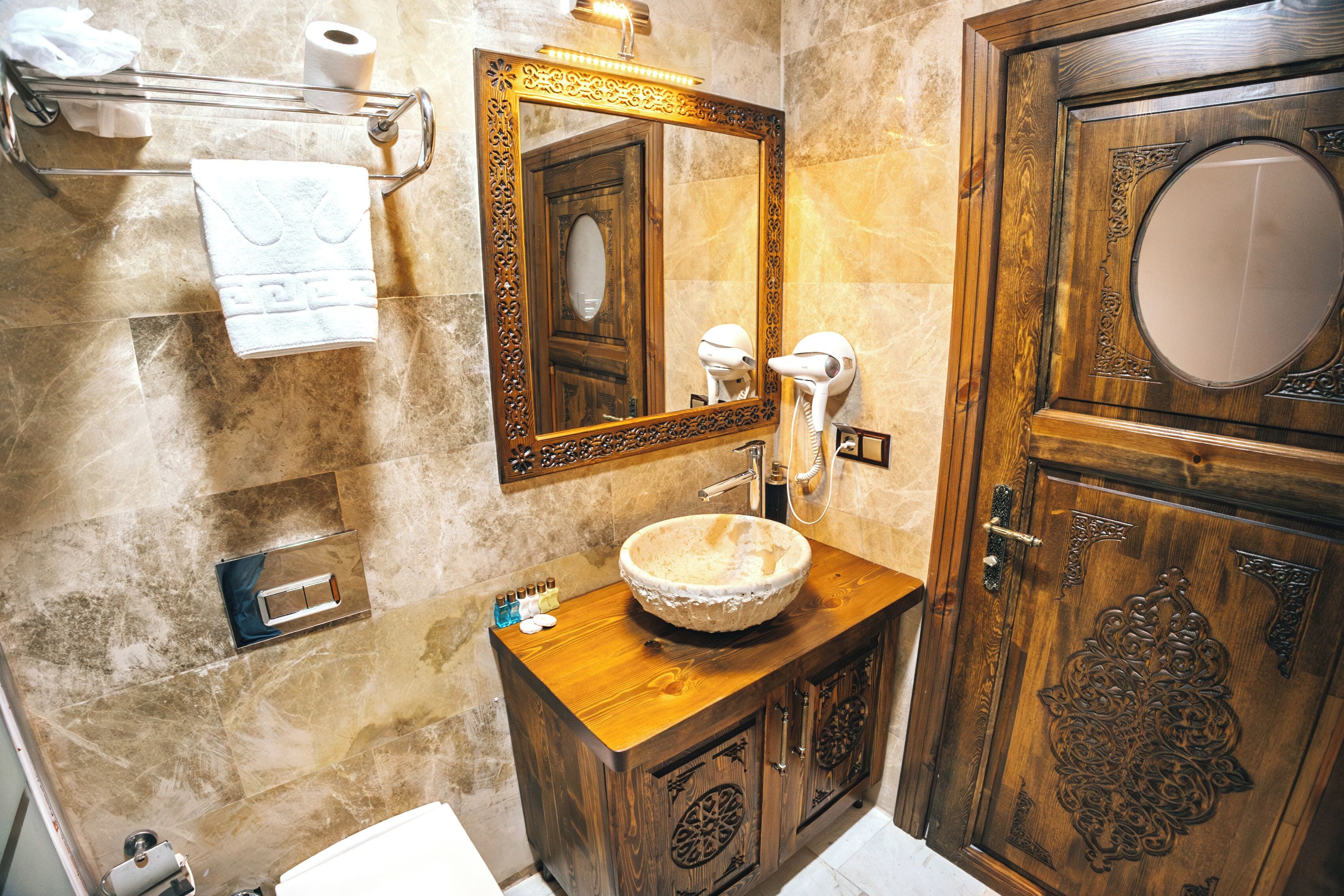 A bathroom with a wooden vanity, a large mirror, and a decorative door.