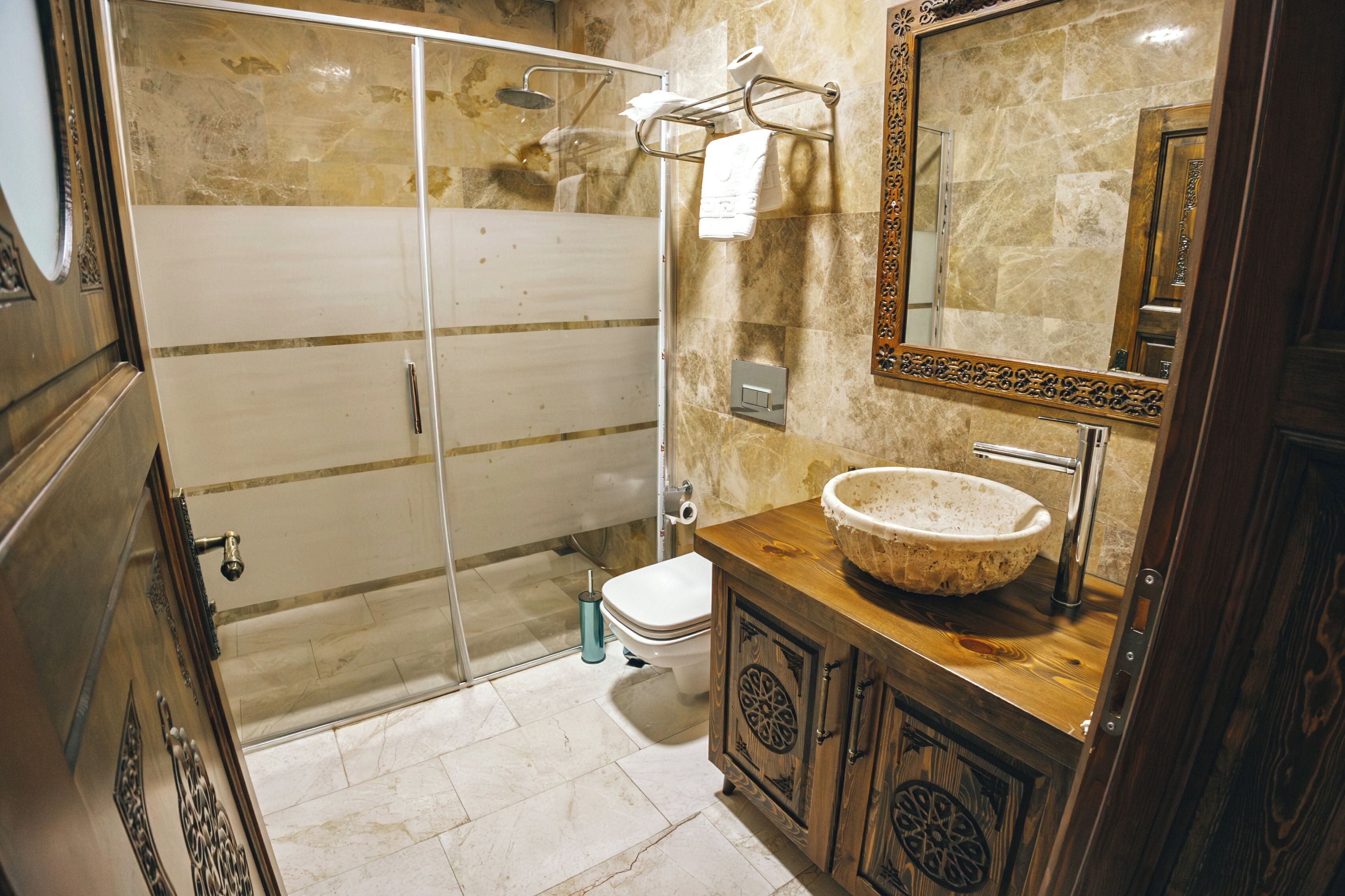 A bathroom with a glass shower enclosure, a wooden vanity with a sink, and a large mirror.