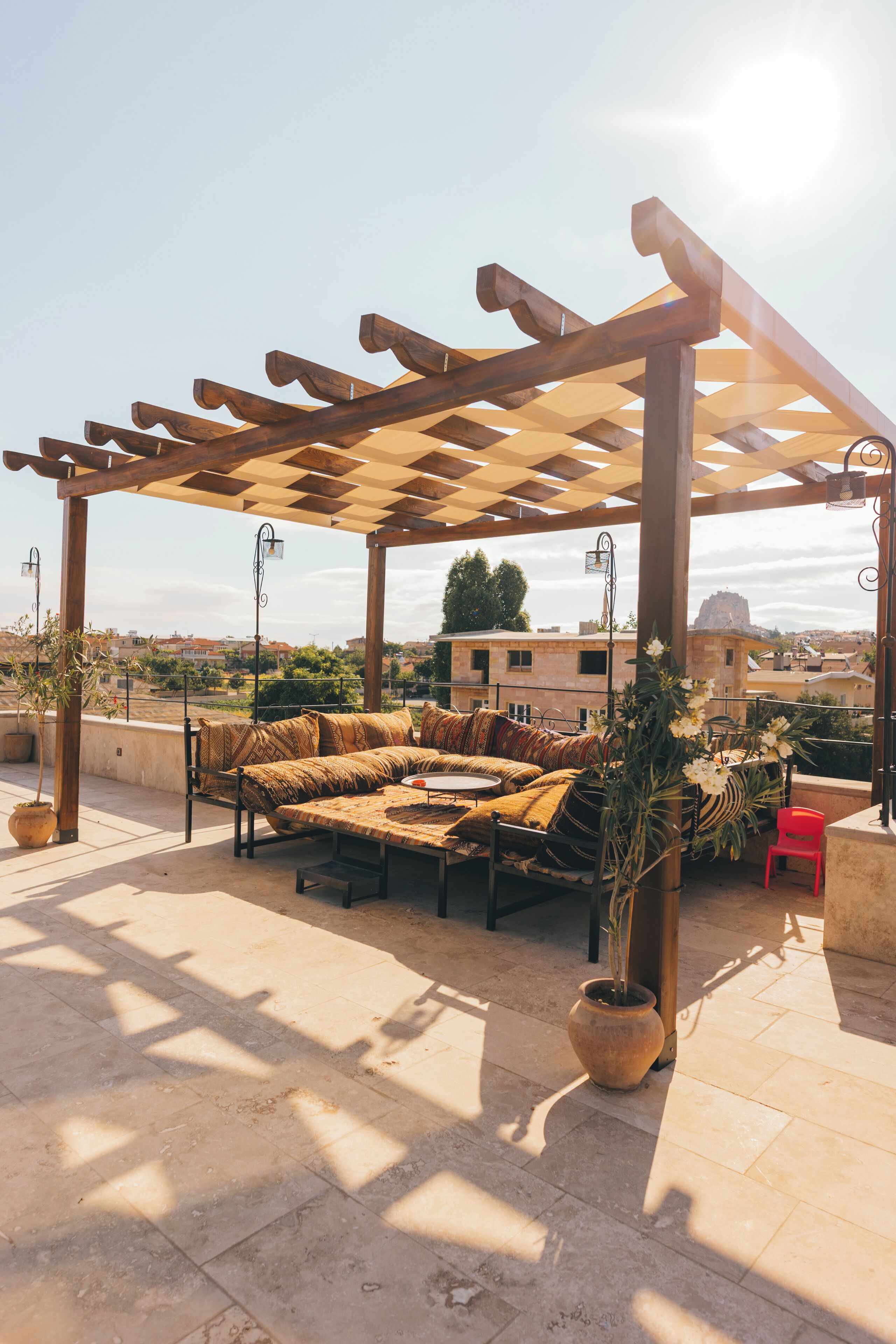 An outdoor seating area with a pergola, a sofa set, and potted plants.