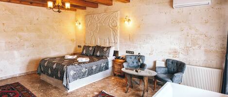 A bedroom with a bed, a small round table, a chair, and a bathtub.