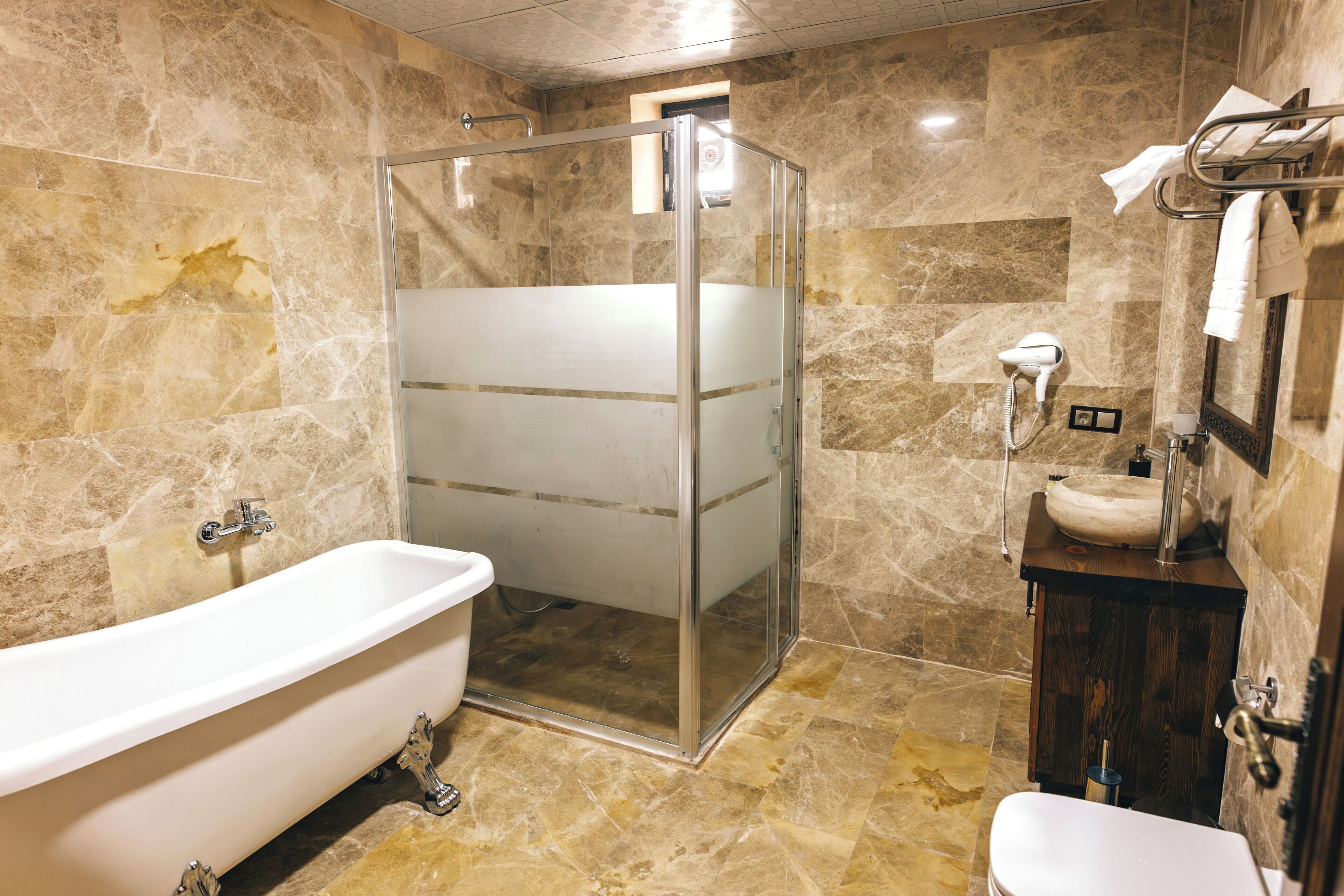 Een badkamer met een douchecabine van glas, een vrijstaand bad, een houten wastafelmeubel en een toilet.