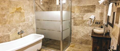 Een badkamer met een douchecabine van glas, een vrijstaand bad, een houten wastafelmeubel en een toilet.