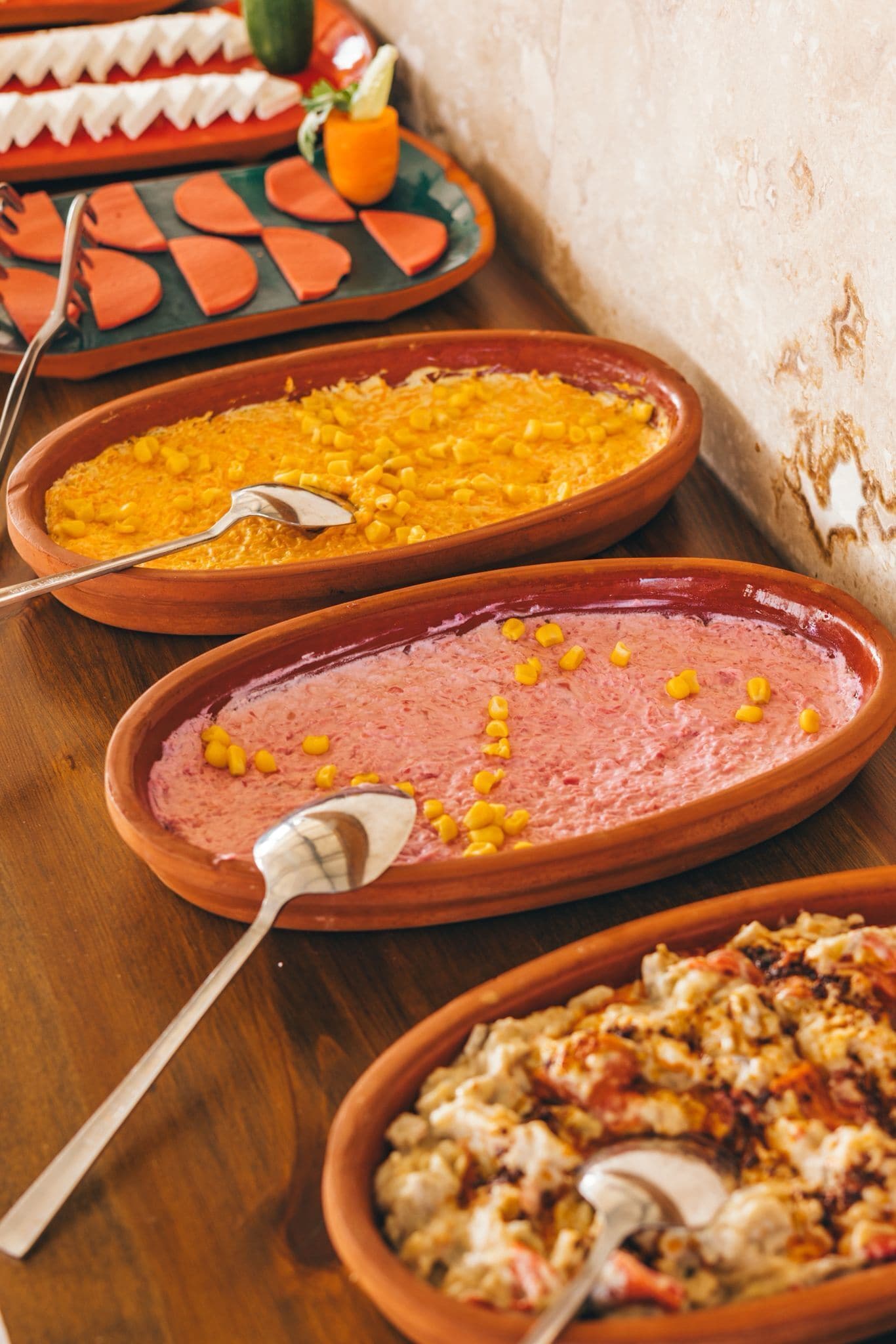 Una mesa con diversos platos, incluyendo un plato de maíz y un guiso de carne, junto con cubiertos.