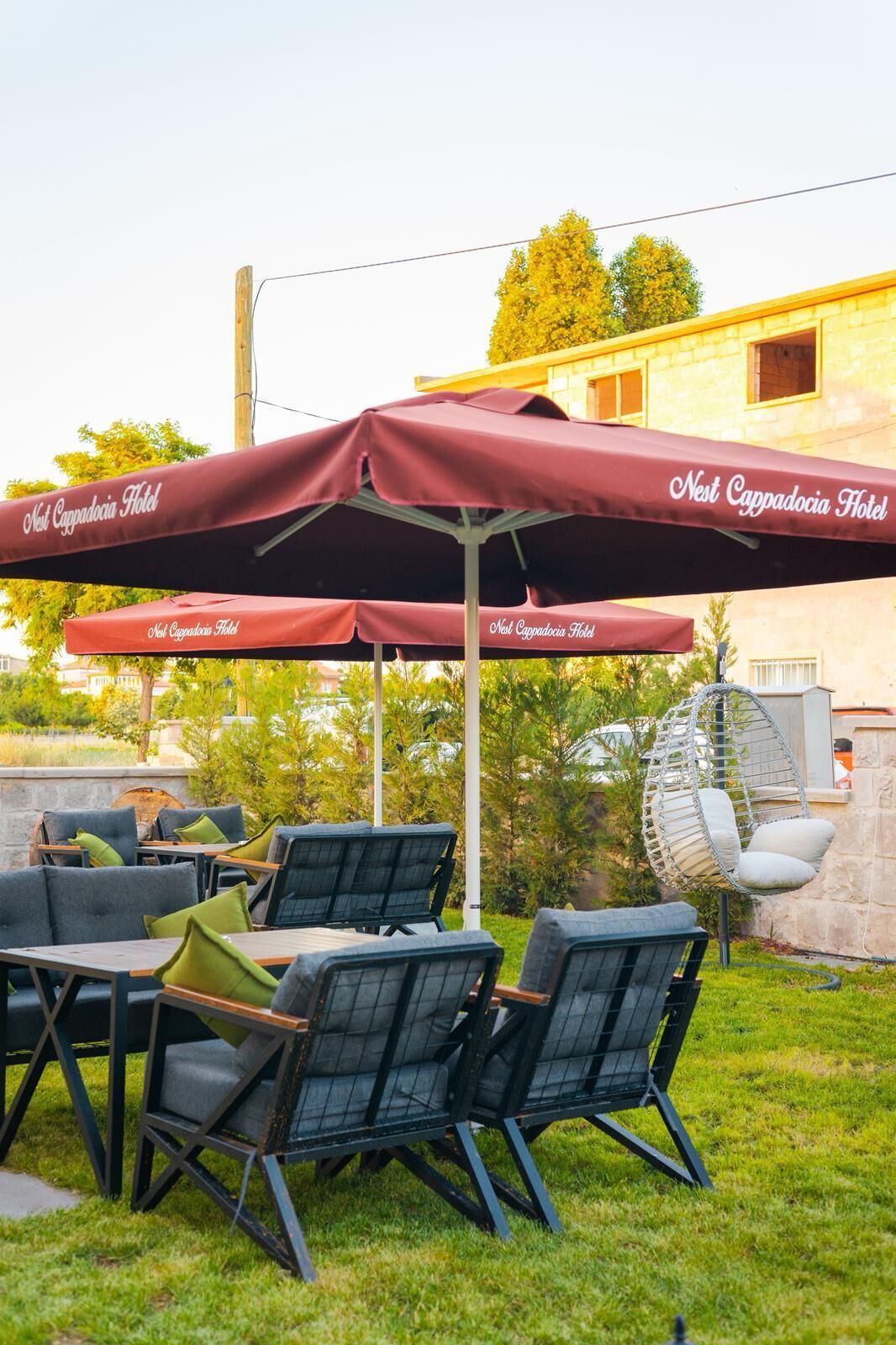 Outdoor seating with umbrellas, a hanging chair, and a stone wall.
