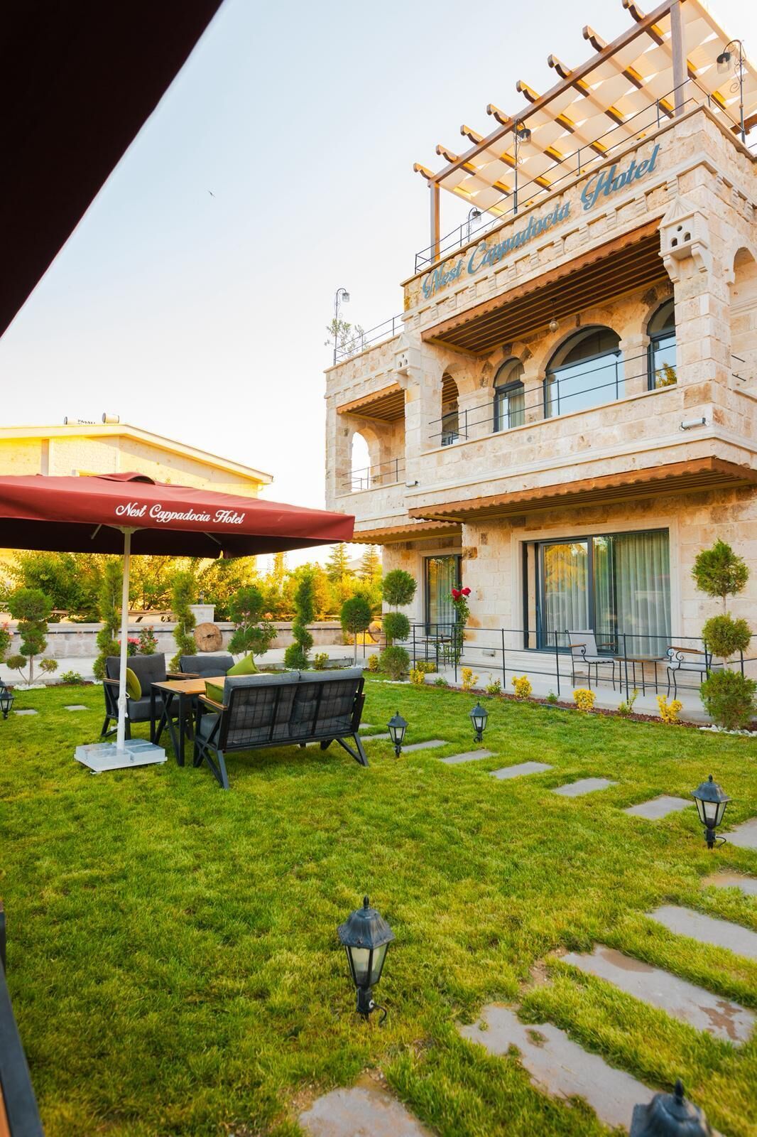Un patio con mesas al aire libre, una sombrilla roja y un edificio de piedra con el texto 