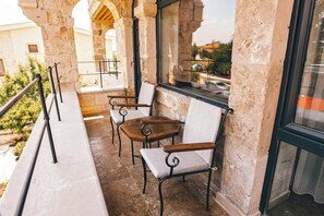 A balcony with stone walls, two wooden tables, and four upholstered chairs. - NEST CAPPADOCIA HOTEL (Nevsehir)