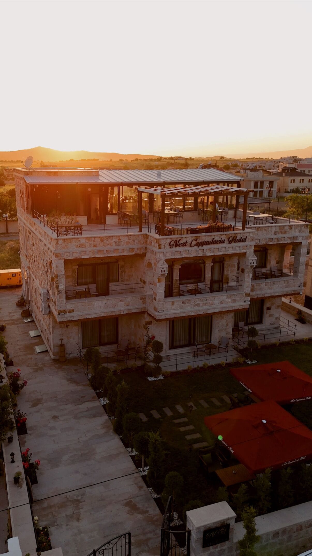 Un hotel de varios pisos con fachada de piedra, zonas de estar al aire libre y vistas del paisaje circundante.