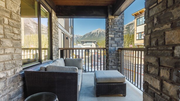 Un balcon doté de meubles en osier, de murs en pierre et offrant une vue sur la montagne.
