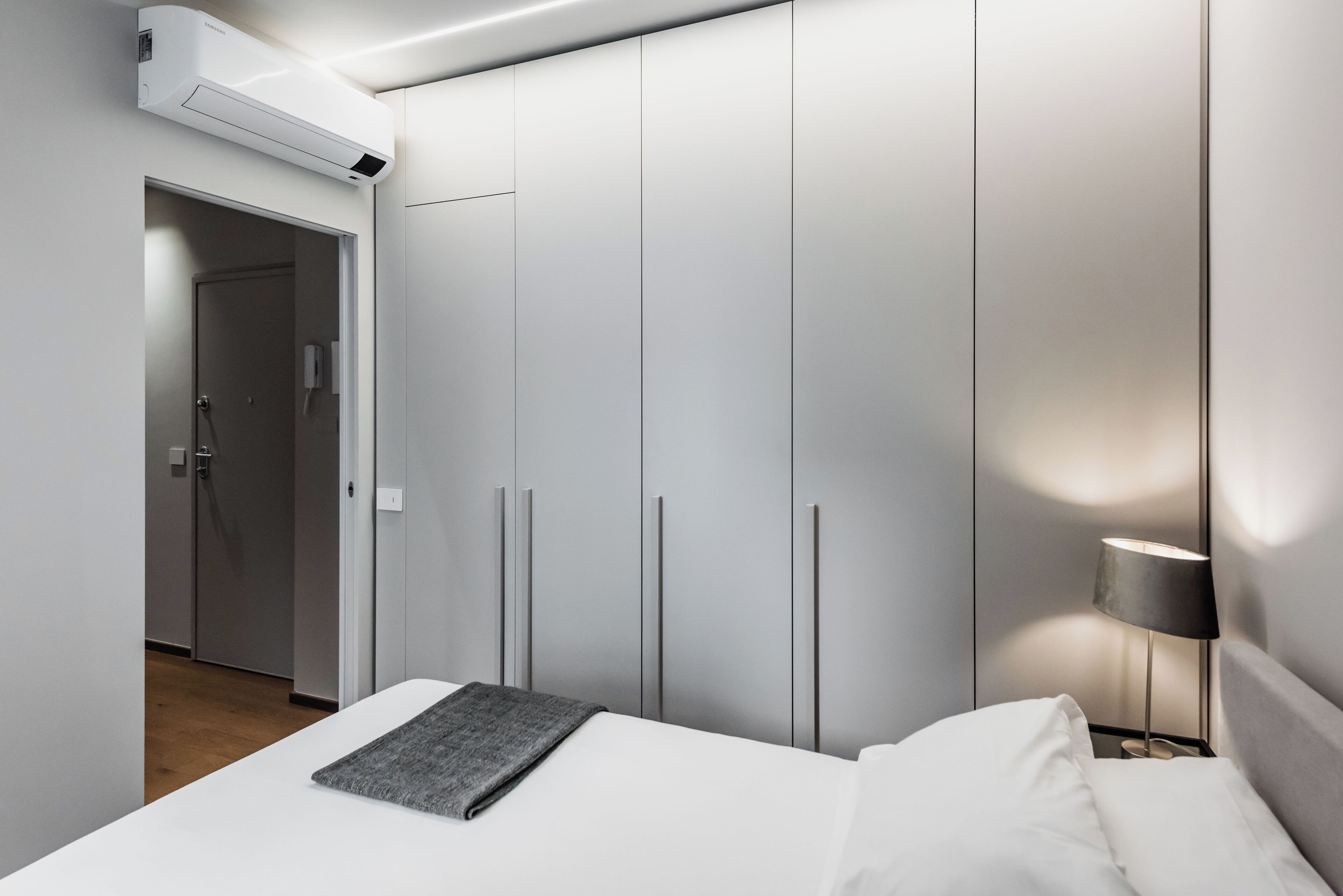 Una camera da letto moderna con un letto, un comodino, una lampada e un armadio.