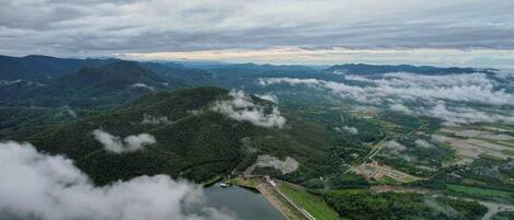 An aerial view of a mountainous landscape with a lake, forested areas, and a small settlement with visible infrastructure.