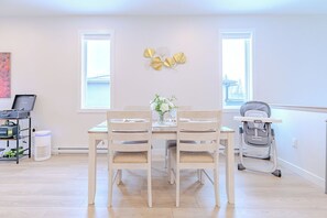 A dining area with a table, chairs, a vase with flowers, and a stroller. - Starz At Night Luxury Suite By Halifax Airport (YHZ) (Lantz)