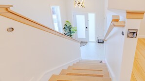 Una escalera de madera con barandilla que conduce a una habitación con puerta y una planta.