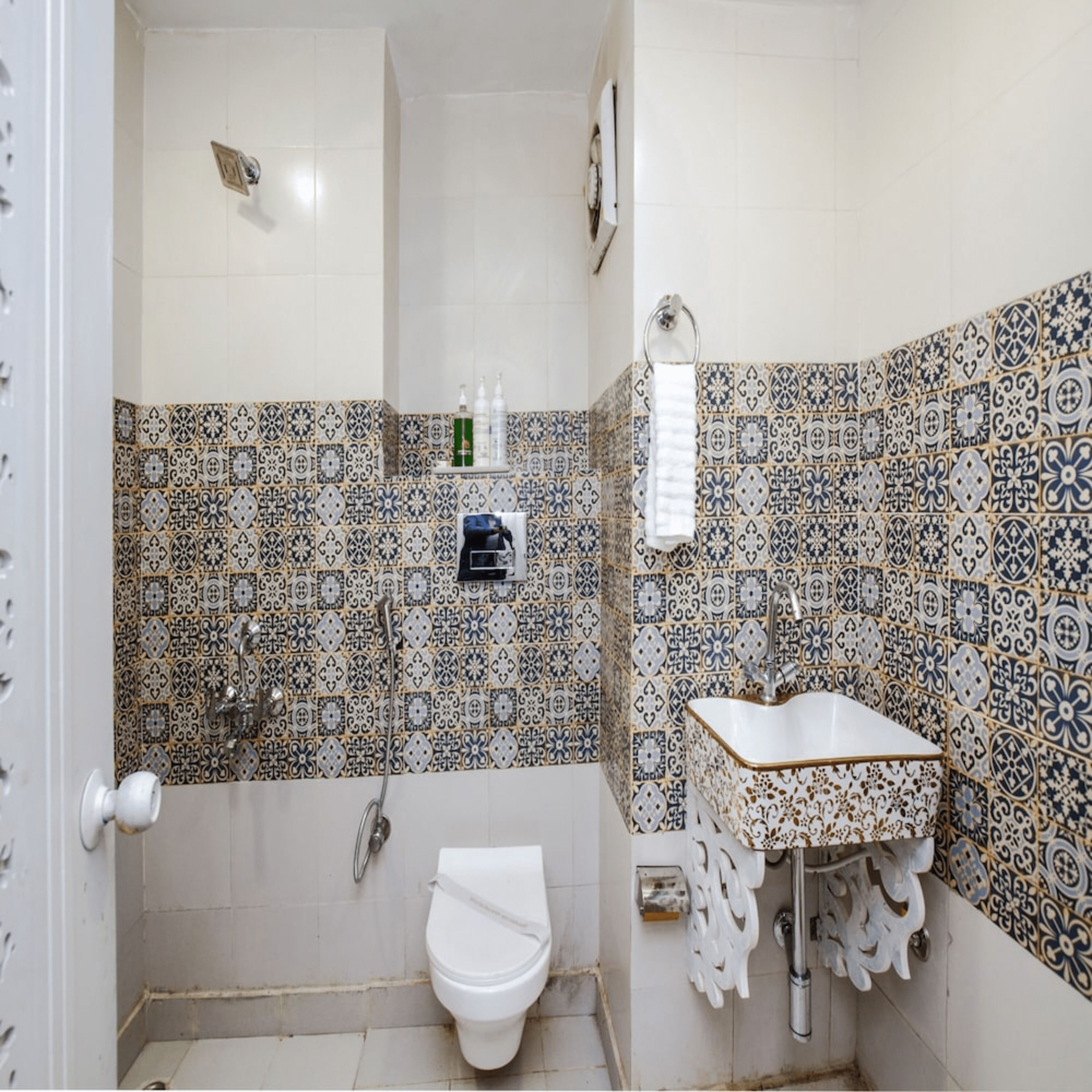 A bathroom with patterned tiles, a toilet, a sink, and a shower.