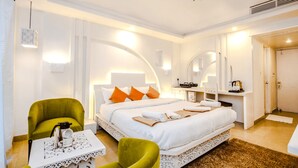 A hotel room with a large bed, two green chairs, a small table with a coffee maker, and a mirror above the bed. - Hotel Snow Princess  (Manali)
