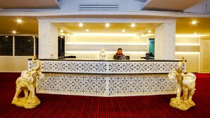 A reception area with a patterned counter, two elephant statues, and a person seated behind the counter. - Hotel Snow Princess  (Manali)