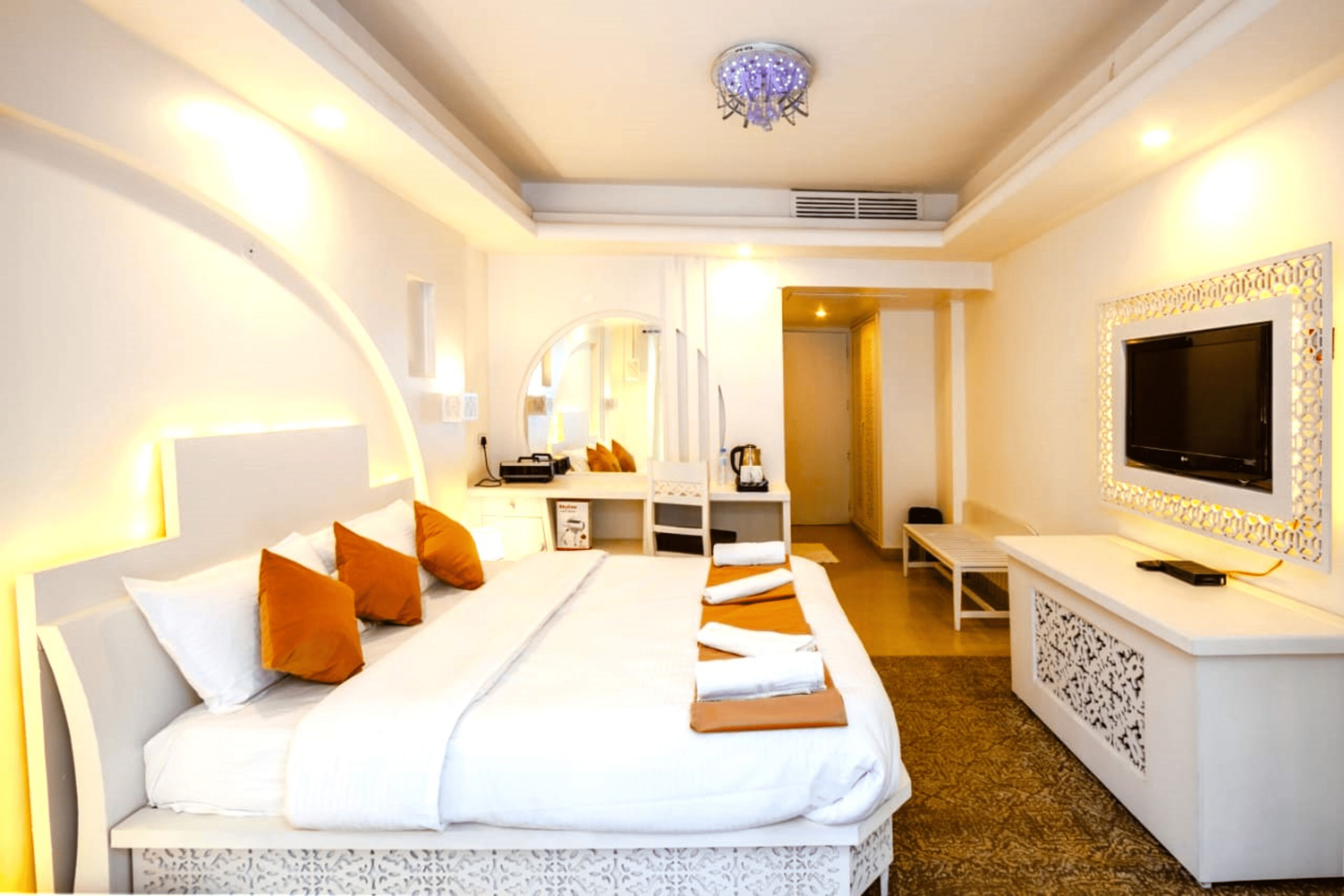 Une chambre d’hôtel avec un grand lit, une télévision, un bureau et un miroir.