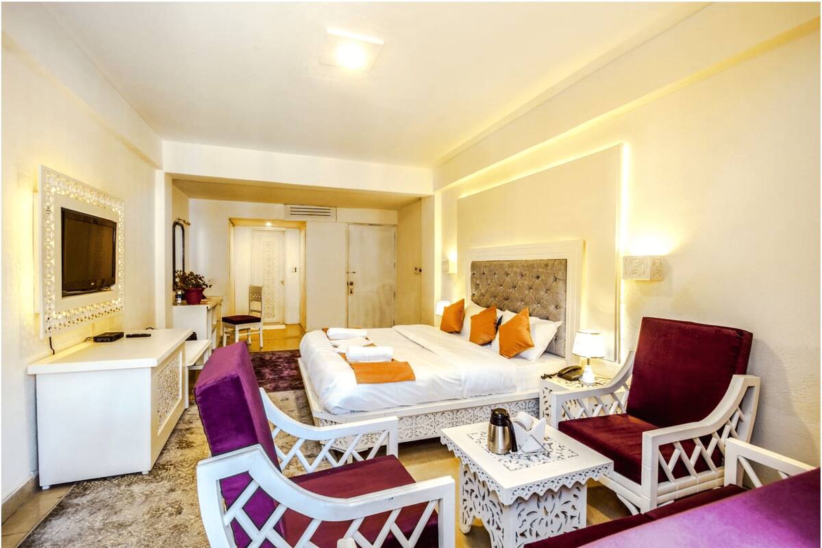 Une chambre d’hôtel avec un lit, des meubles blancs, un bureau et une chaise.