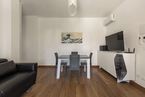 Un soggiorno moderno con un tavolo da pranzo, un divano in pelle nera e un televisore su un mobile bianco.