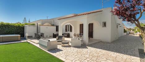 A modern house with a patio, outdoor seating, and a well-maintained lawn.