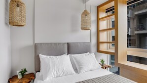 A modern bedroom with a large bed, two hanging wicker lamps, a wooden headboard, and a view of the outside through a large window. - Sanders Old Port Thessaloniki (Thessaloniki)
