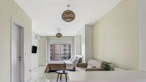 A modern living room with a marble floor, a sofa, a coffee table, and a large window with a view of a building. - Sanders Old Port Thessaloniki (Thessaloniki)