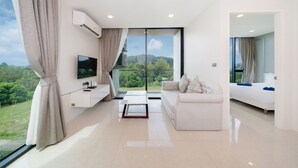 Ein modernes Wohnzimmer mit einem großen Fenster, einem Flachbildfernseher, einer Couch und einem Bett.