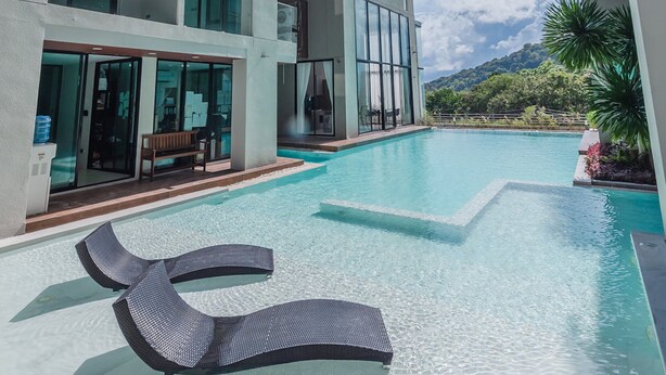 Ein modernes Hotel mit Schwimmbad, Liegestühlen und Blick auf die Berge.