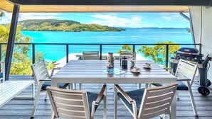 A dining area with a table and chairs, a grill, and a view of the sea. - Shorelines 17 - Hamilton Island  (Hamilton Island)