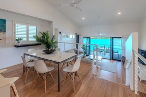 Enjoy a bright and airy space with a dining area, balcony overlooking a body of water, and a ceiling fan.