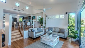A modern living room with a sofa, coffee table, and a staircase leading to an upper level. - Shorelines 17 - Hamilton Island  (Hamilton Island)