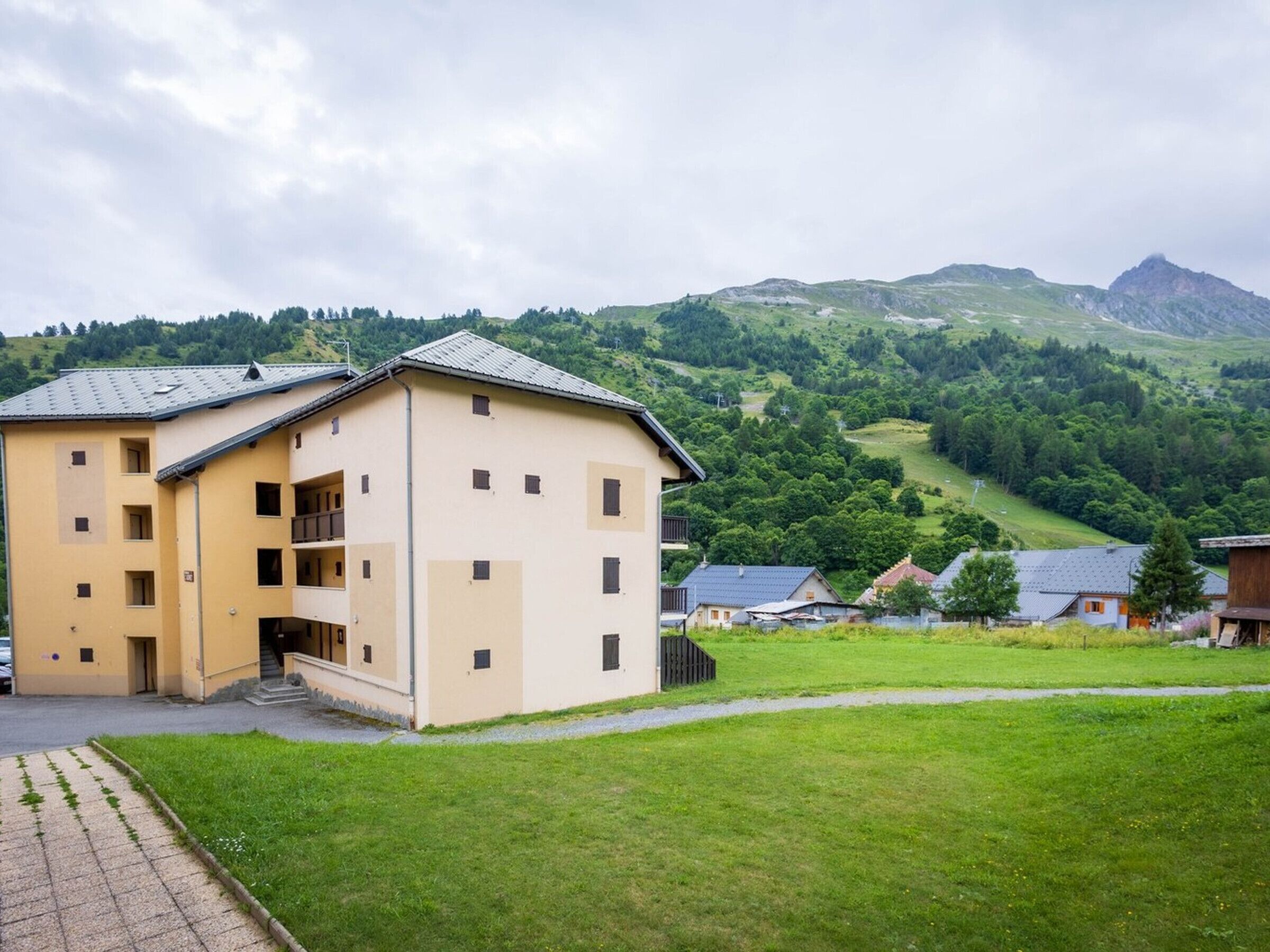 A multi-story building with a flat roof, a central entrance, and a small balcony.