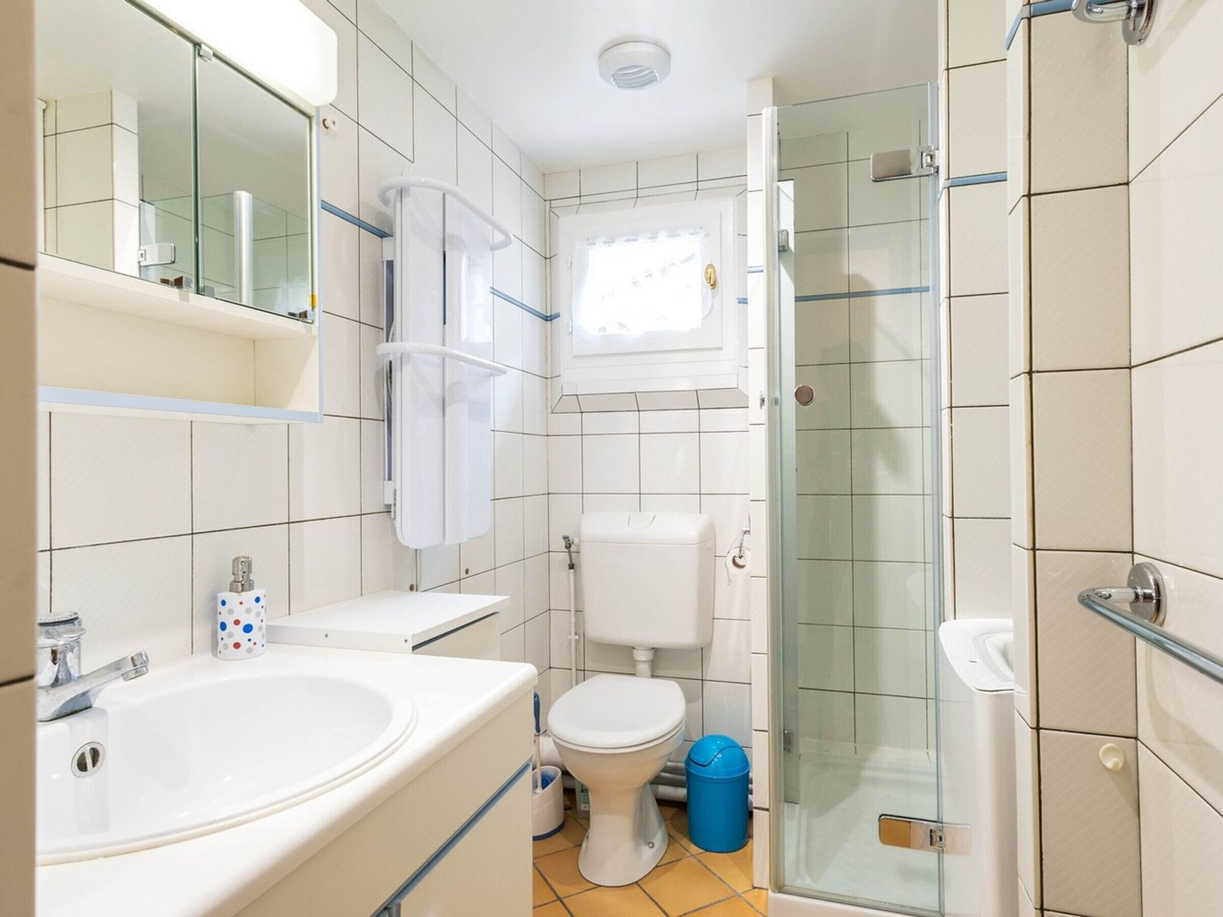 Et badeværelse med vask, toilet og glasvæg omkring brusenichen.