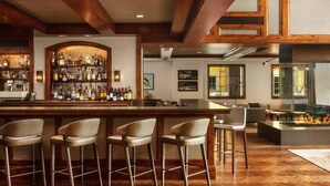 A bar area with a wooden ceiling, a bar counter with stools, and a fire feature. - RITZ CARLTON RESIDENCE - Vaill Colorado,  3 bedroom, lovely mountain views . (Vail)