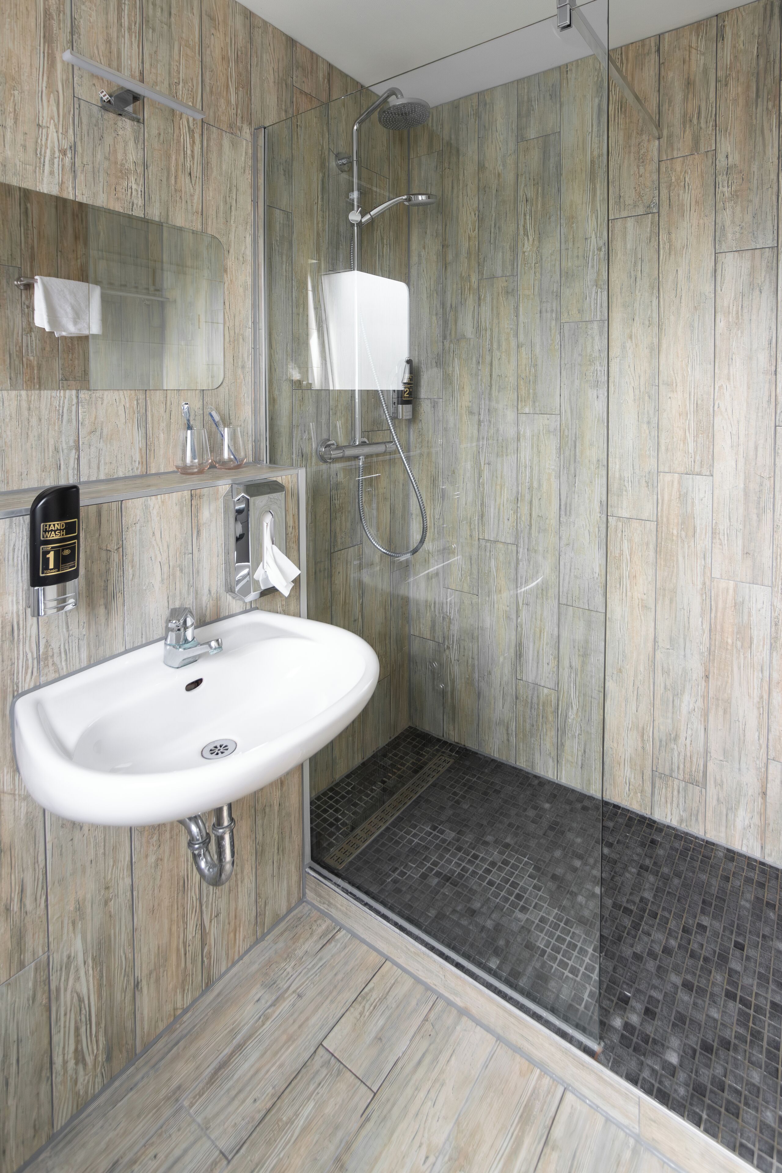 Een moderne badkamer met een douchecabine van glas, een wit wastafelmeubel en een houten wandpaneel.