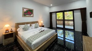A hotel room with a bed, nightstands, a painting, and a view of the outdoors. - Rai Wood Carver and Homestay (Ubud)