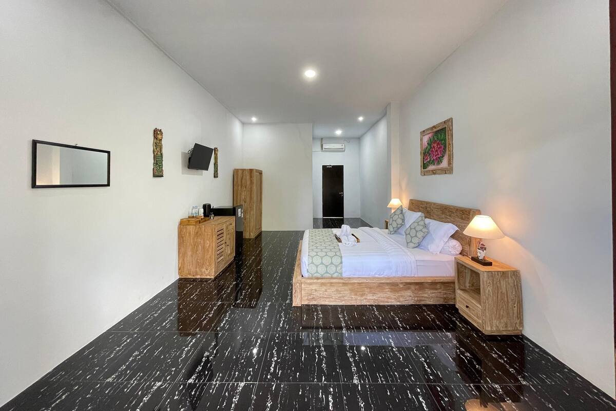 A hotel room with a bed, bedside tables, a wardrobe, a flat-screen TV, and a painting on the wall.
