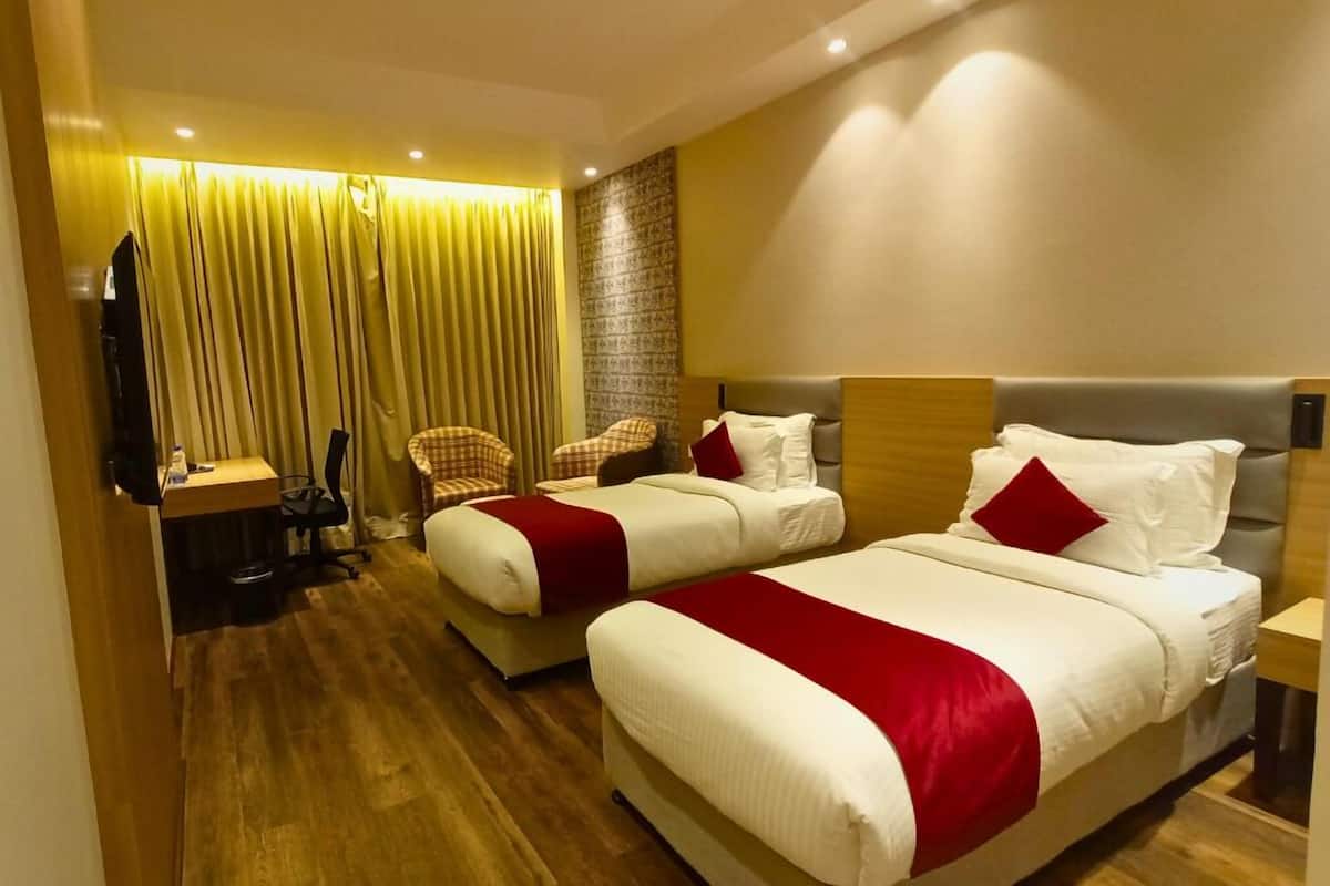 A hotel room with two beds, a desk, and a chair.