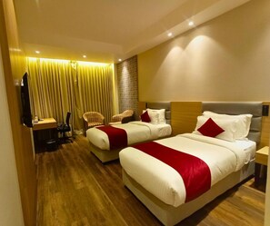Habitación de hotel con dos camas, un escritorio y una silla.