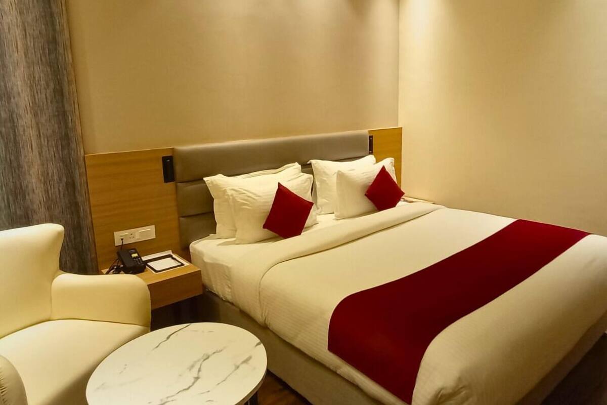 A hotel room with a bed, a nightstand, a chair, and a small round table.