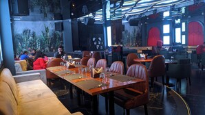 Een restaurant met hoge tafels en lederen stoelen, een muurschildering en een bar.