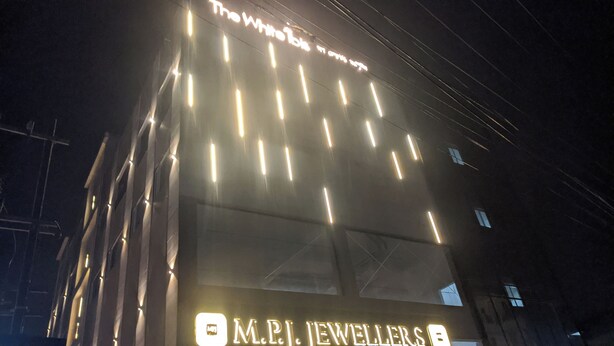 Een gebouw met verlichte reclameborden voor 'The White Rabbit' en 'M.P.J. Jewellers'.