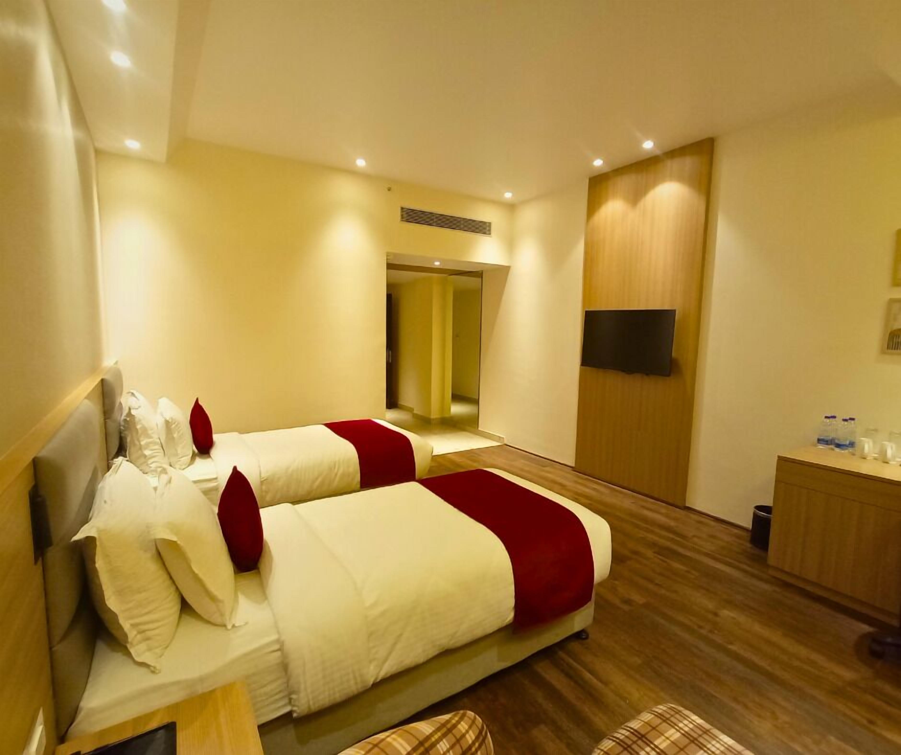 Habitación de hotel con dos camas, piso de madera, un escritorio pequeño y un espejo.
