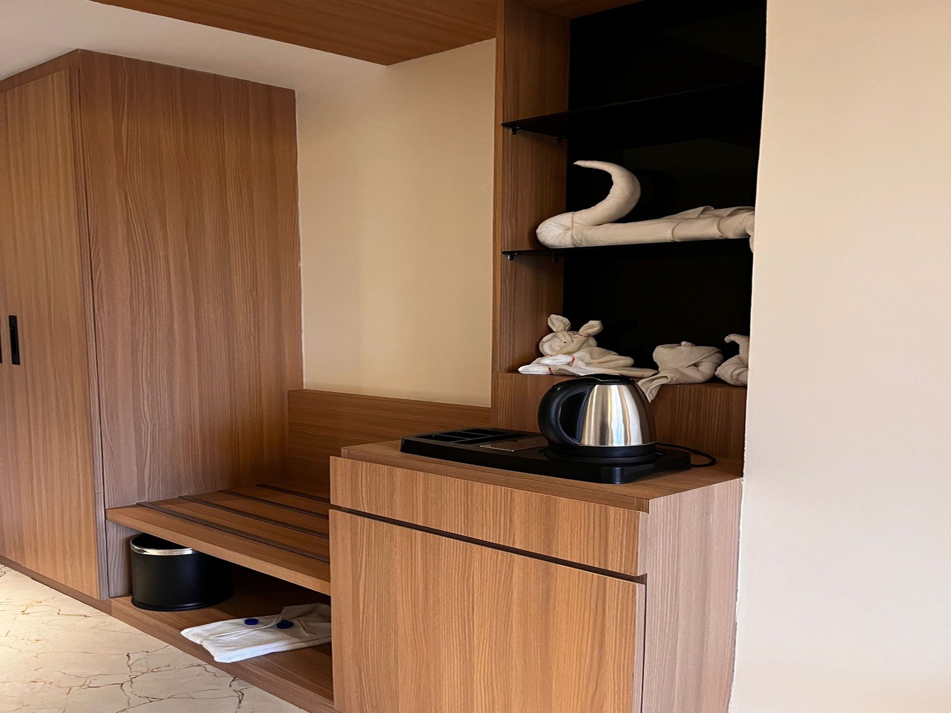 Une petite cuisine équipée avec des meubles en bois, une bouilloire et une machine à café noire posée sur le plan de travail.