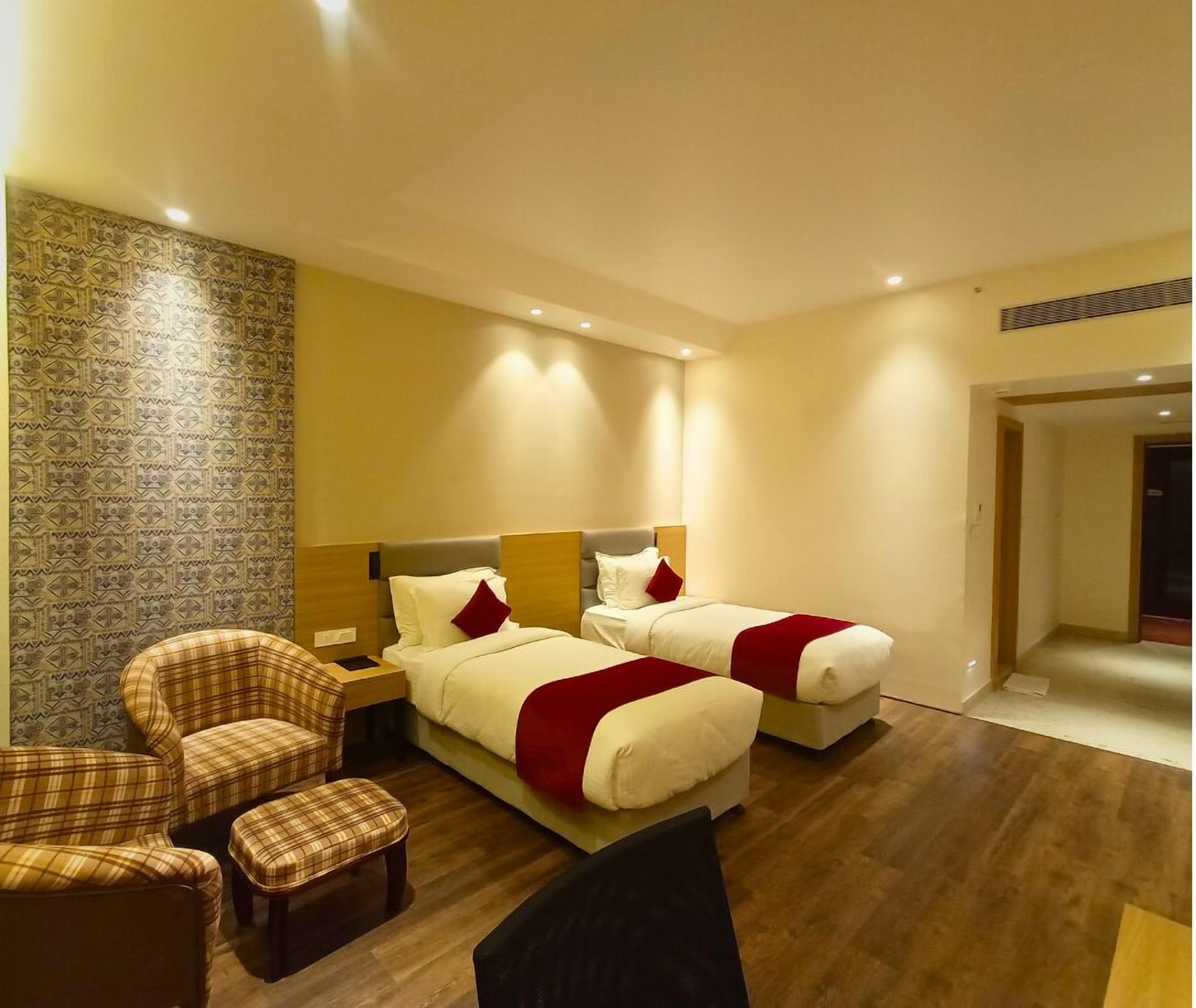 Een hotelkamer met twee bedden, een slaapbank en een fauteuil.
