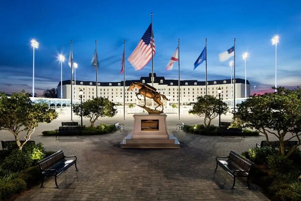 A courtyard with a central statue, benches, and flags. - Sunny Springs Oasis (Ocala)