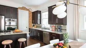 Une cuisine moderne avec des meubles de couleur sombre, des appareils en acier inoxydable et un îlot central doté de tabourets.
